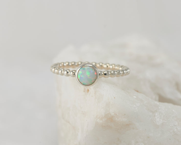 Silver opal beaded ring on white rock