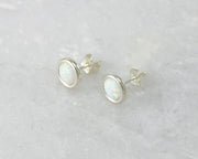 Silver stud opal earrings on white marble