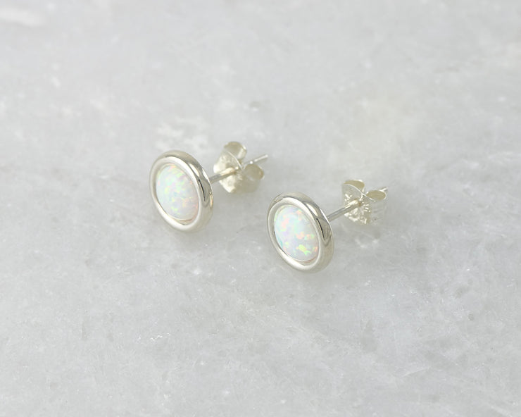 Silver stud opal earrings on white marble