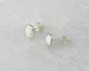 Silver stud opal earrings on white marble