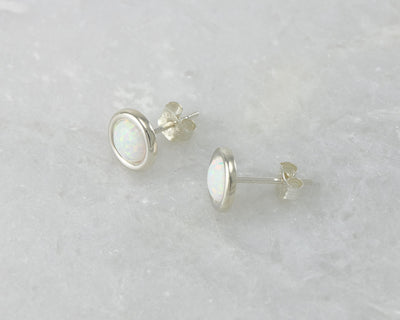 Silver stud opal earrings on white marble