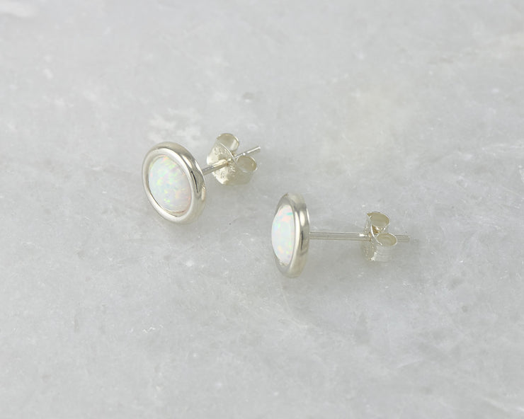 Silver stud opal earrings on white marble