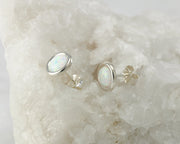 Silver opal stud earrings on white rock