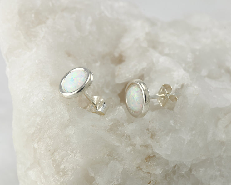 Silver opal stud earrings on white rock