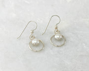 Silver polished pearl hoop earrings on white marble