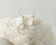 Silver pearl hoop earrings on white rock