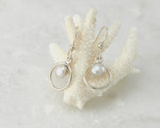 Silver pearl hoop earrings on coral