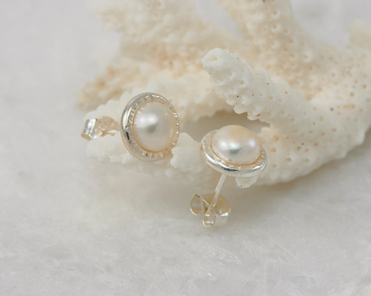 silver pearl stud earrings on coral