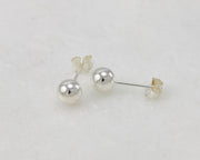 Silver polished stud earrings on white marble