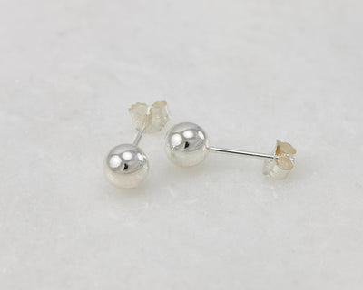 Silver polished stud earrings on white marble
