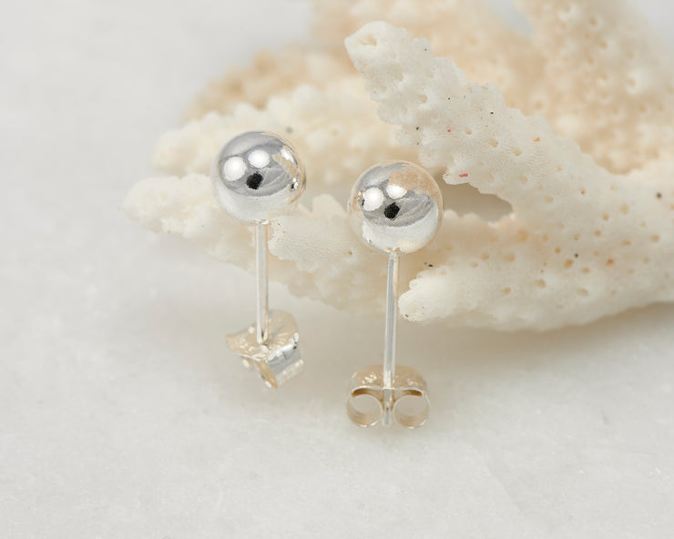 Silver stud earrings on coral
