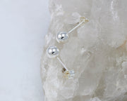 Silver stud ball earrings on white rock