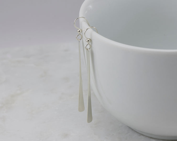 silver bar earrings on white cup