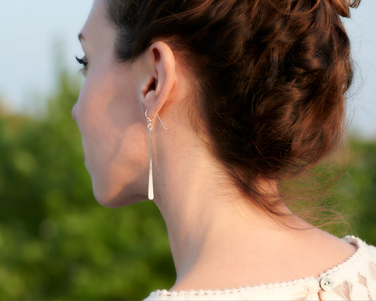woman facing away wearing silver bar earrings