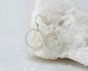Silver beaded circle hoop hoop earrings on white rock