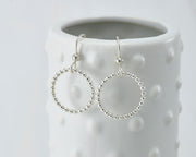 Silver polished beaded circle hoop earrings on dotted vase