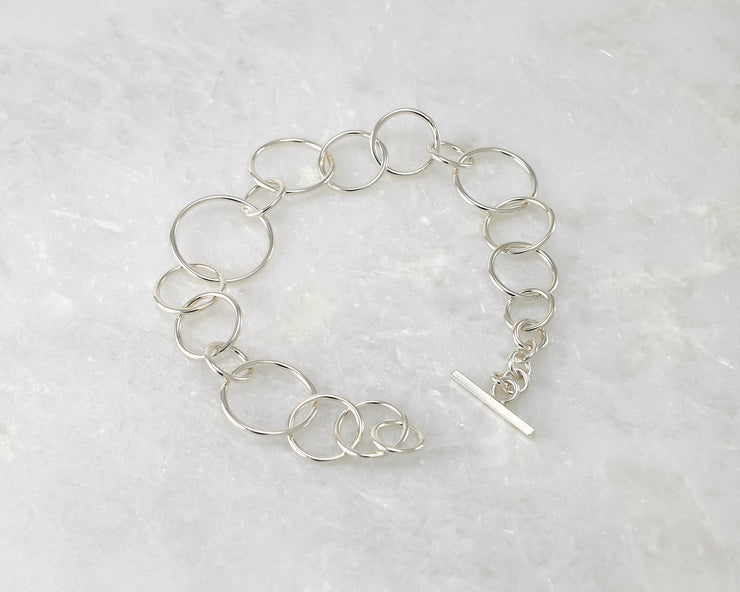 latch style chain link silver bracelet open on marble