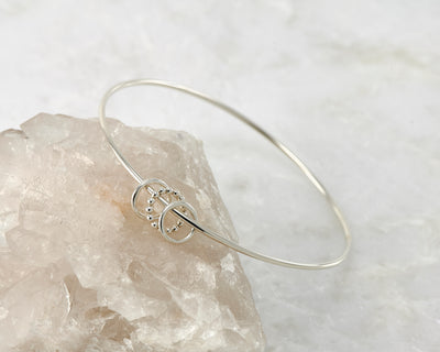 Silver charms bangle on white rock