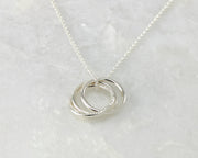 Silver interlocking unity necklace on white marble