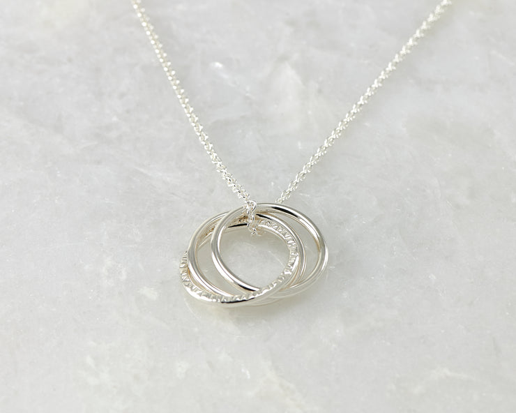 Silver interlocking unity necklace on white marble