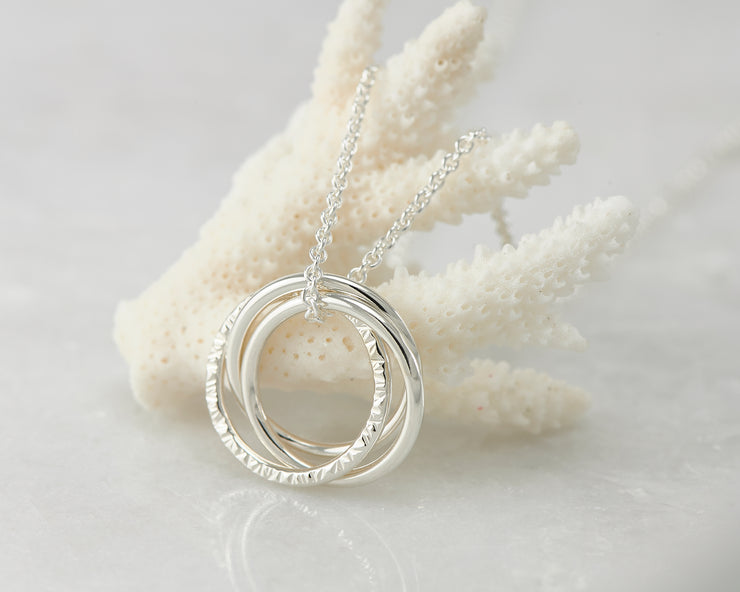 Silver interlocking unity necklace on coral