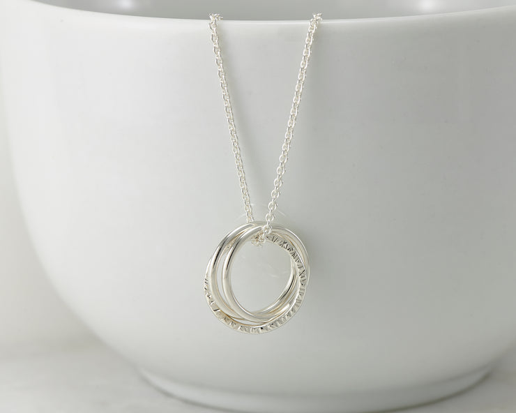 Silver interlocking unity necklace on white cup