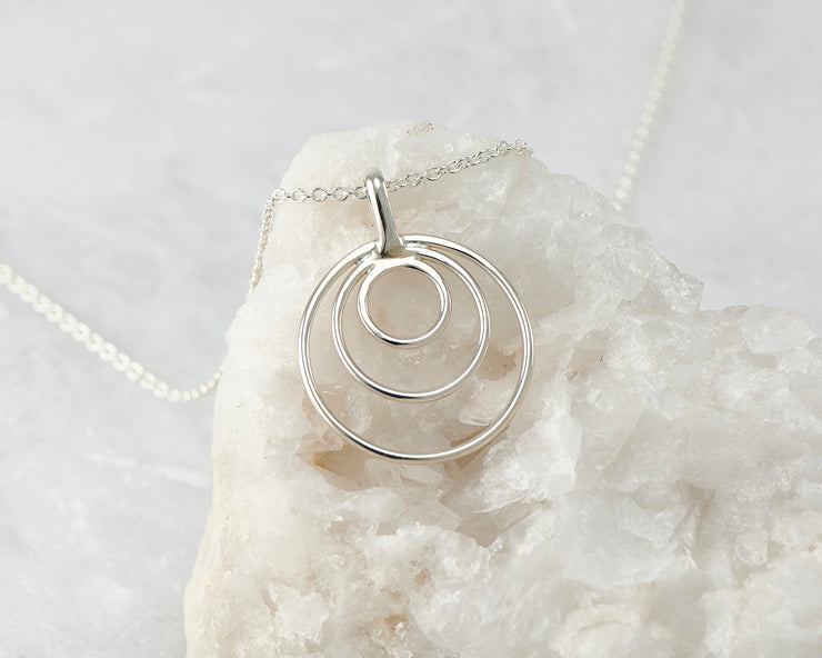 silver circles necklace on white rock