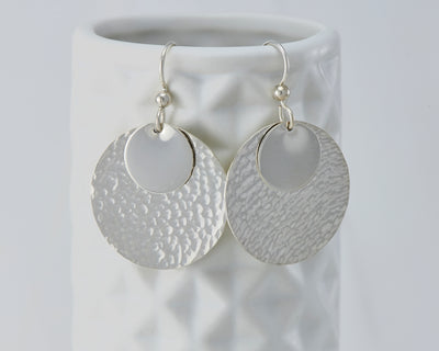 Silver hammered discs earrings on geometric vase