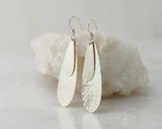 Silver teardrops earrings on white rock
