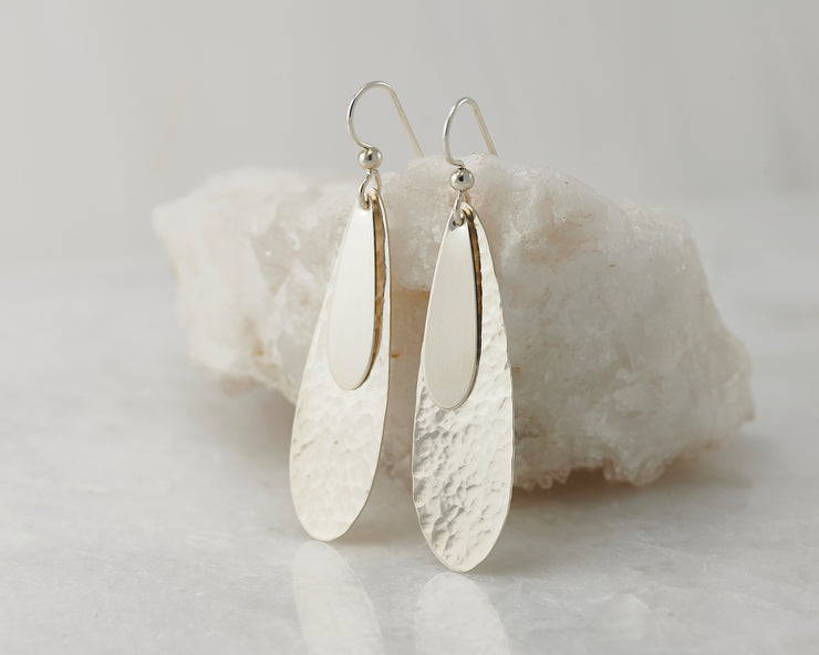 Silver teardrops earrings on white rock