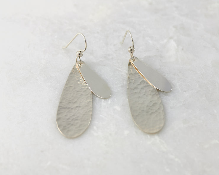 Silver polished teardrops earrings on white marble