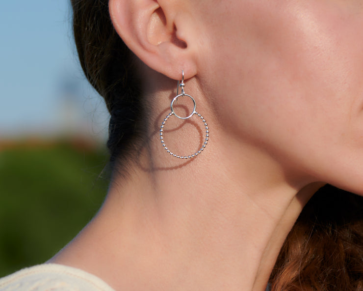 Close-up of woman wearing silver hoop beaded circles earrings