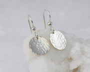 Hammered Dangle Earrings shown on a white rock