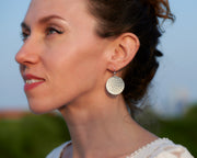 Silver dangle earrings being worn by a woman