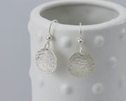 Circle Hammered earrings hanging on a dotted vase
