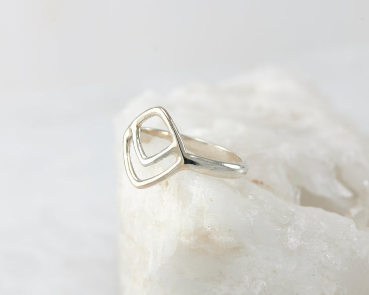 Silver geometric ring on white rock