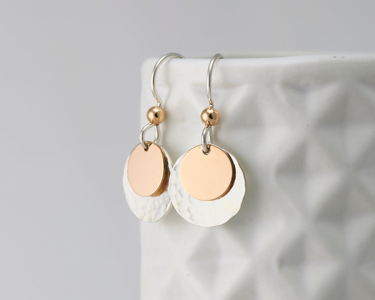 silver and gold disc earrings on geometric vase