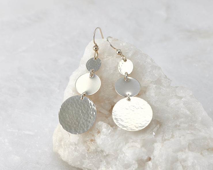 Hammered Dangle Earrings shown on a white rock