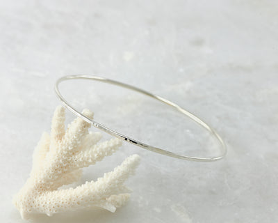 silver latch hammered bangle bracelet balanced on coral