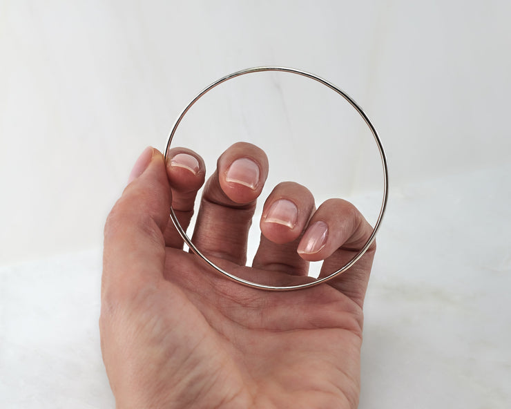 woman holding silver bangle bracelet