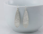 silver hammered teardrop earrings on white cup