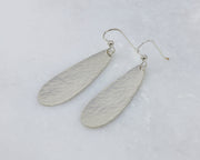 silver hammered teardrop earrings on white marble