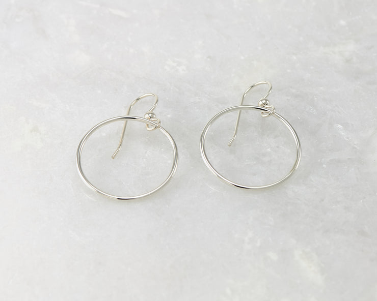 Silver medium hoop earrings on white marble