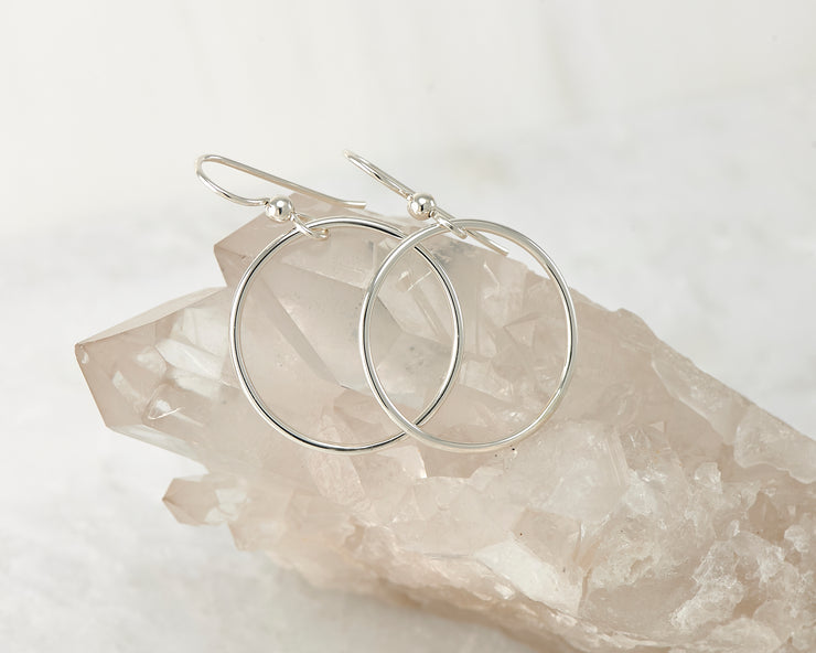 Silver medium hoop earrings on crystal rock