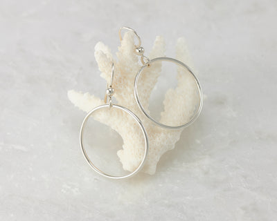 Silver medium hoop earrings on coral