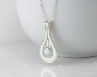 Silver opal pendant on white cup