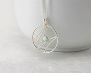 silver opal pendant necklace hanging from white cup