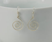 silver spiral earrings on white cup