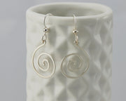 silver spiral earrings on geometric vase
