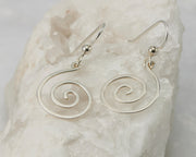 Silver dangle spiral earrings on white rock